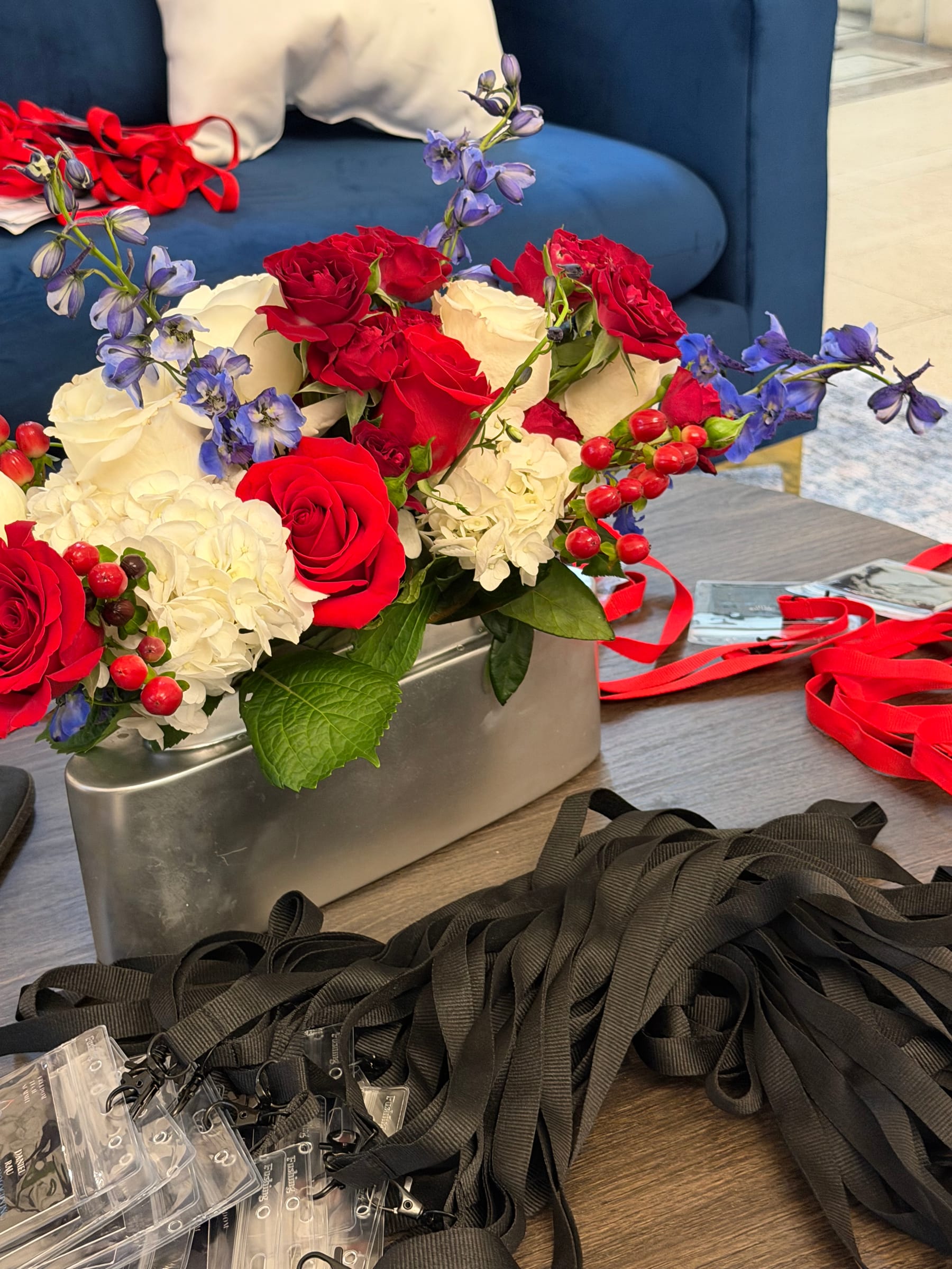 Freedom Tech Summit floral styling and credentials Red, white, and blue floral arrangement with roses, hydrangeas, and delphinium beside summit lanyards and credentials