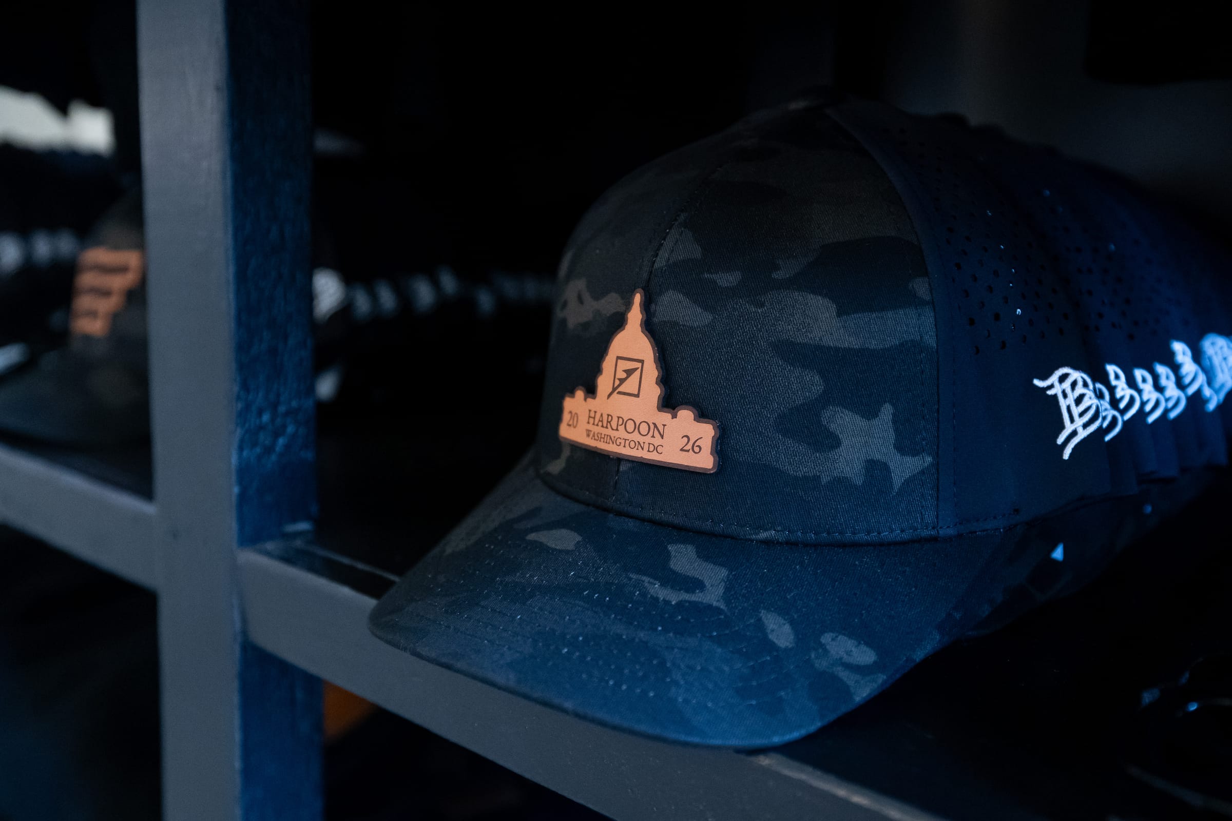 Harpoon merchandise detail Harpoon Washington DC camouflage cap with leather Capitol patch on the retail display shelf